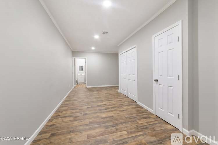 A long hallway with white doors and wooden floors.