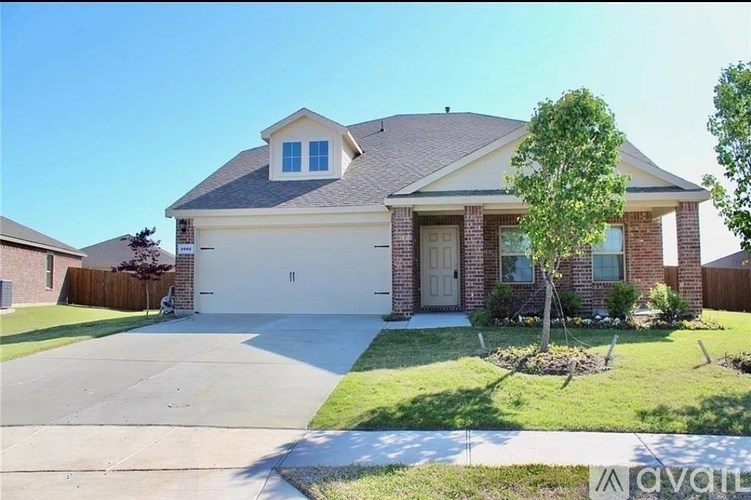A house with a garage and a tree in front.