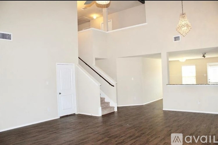 A spacious room with wooden floors and a staircase leading to another level.