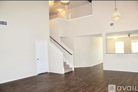 A spacious room with wooden floors and a staircase leading to another level.
