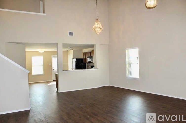 A large empty room with wooden floors and a chandelier hanging from the ceiling.