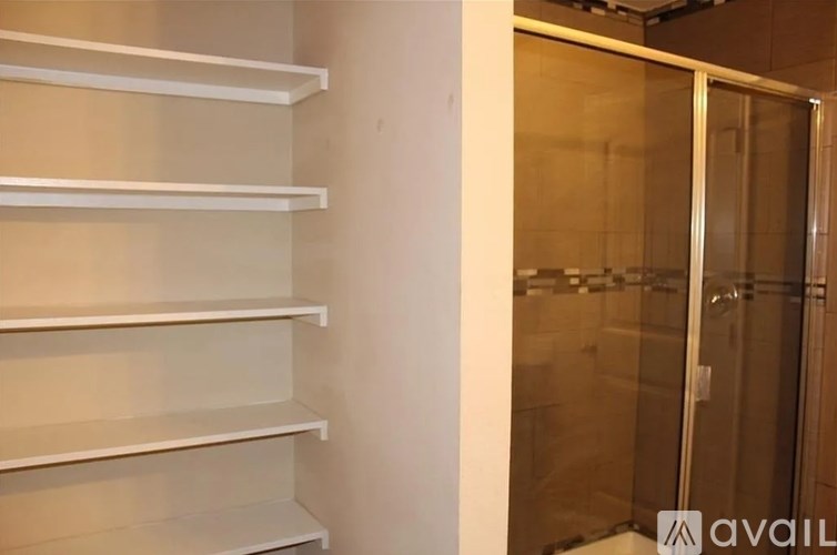 A white shelving unit with a glass door is in the corner of a room.