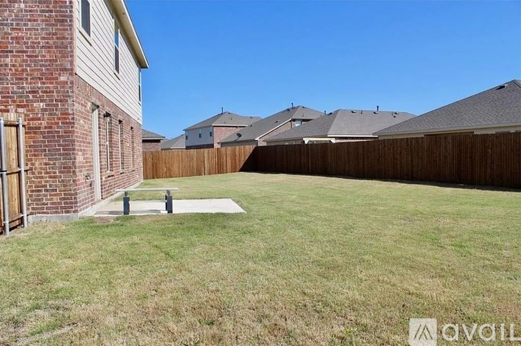 A backyard with a wooden fence and a brick house.