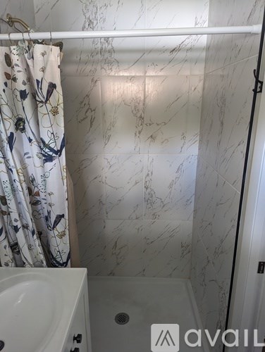 A bathroom with a marble wall and a shower.