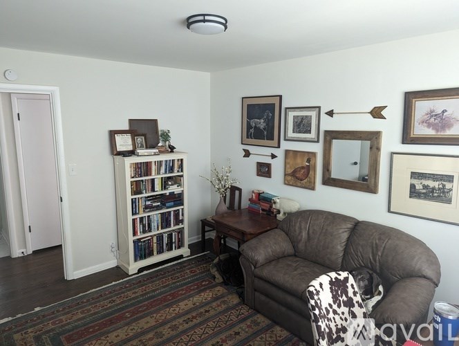 A living room with a couch, a bookshelf, and pictures on the wall.