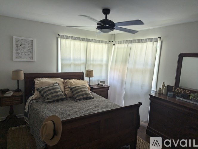A bedroom with a bed, nightstand, and a wall-mounted mirror.