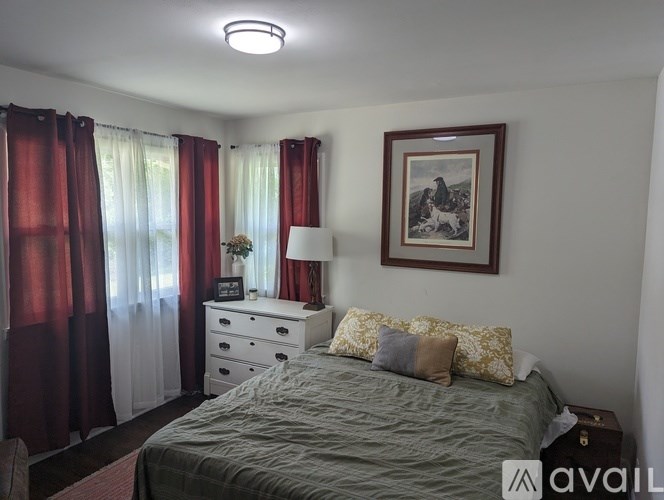 A bedroom with a bed, dresser, and a painting on the wall.