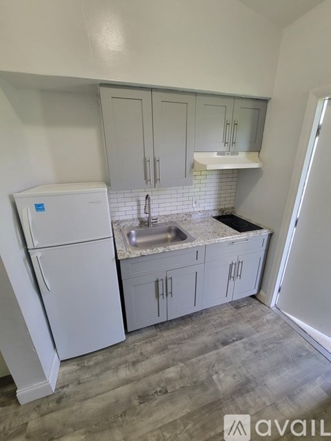 A kitchen with a white fridge, cabinets and a sink.