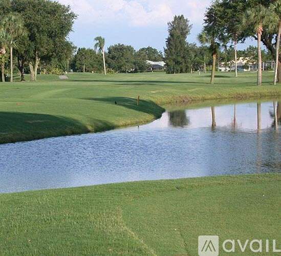 A golf course with a pond and trees in the background.