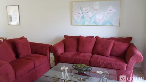 A living room with red couches and a glass coffee table.