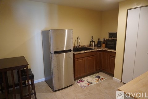 A kitchen with a stainless steel refrigerator and wooden cabinets.