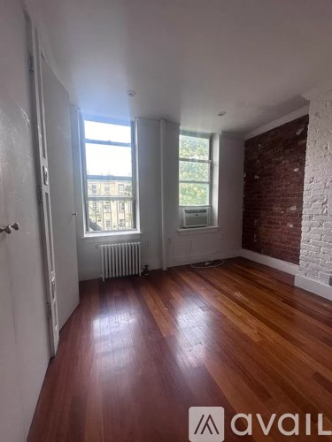 A room with wooden floors and a brick wall.
