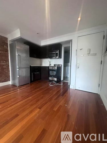 A kitchen with wooden floors and a brick wall.