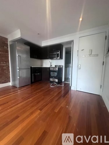 A kitchen with wooden floors and a brick wall.