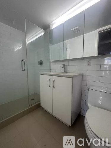 A white bathroom with a glass shower door and a white toilet.