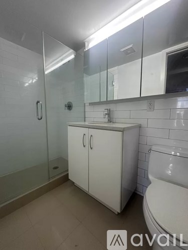 A white bathroom with a glass shower door and a white toilet.