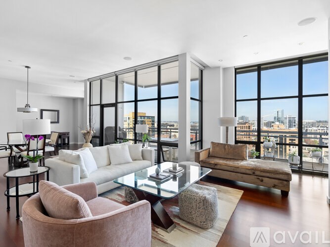 A living room with a white sofa, a glass table, and a large window overlooking the city.