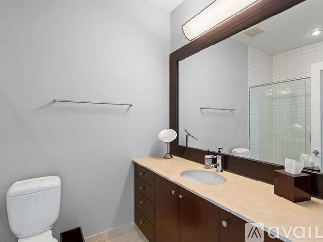 A bathroom with a toilet, sink, mirror, and shelves.