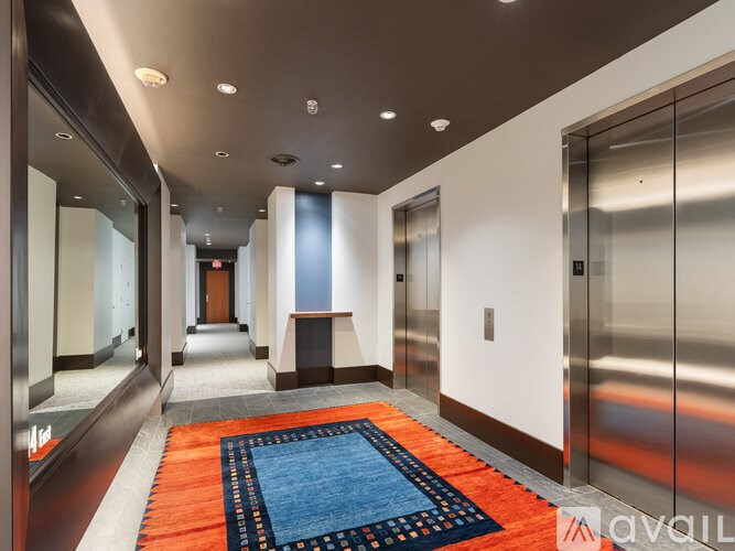 A hallway with a blue and orange carpet and a red elevator.