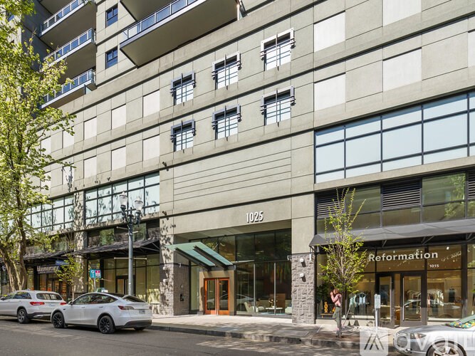 A street view of a building with cars parked in front and a storefront with the name Reformation.