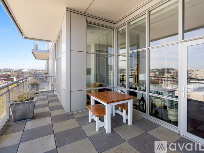 A balcony with a table and chairs overlooking a cityscape.