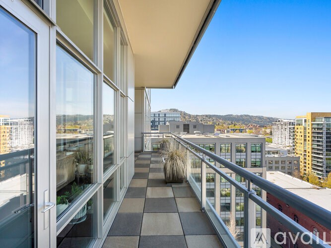 A balcony with a metal railing and glass doors overlooks a cityscape.
