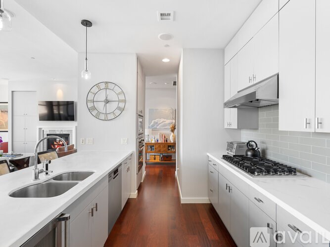 A modern kitchen with white cabinets and a wooden floor.