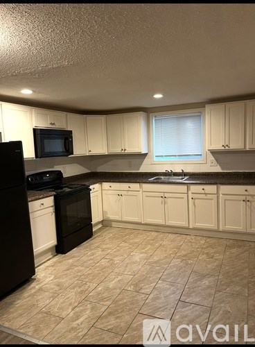 A kitchen with black appliances and white cabinets.