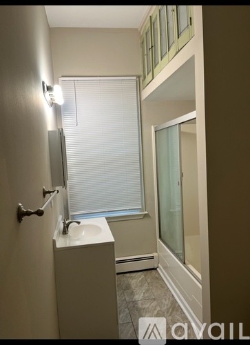 A bathroom with a sink, mirror, and window.