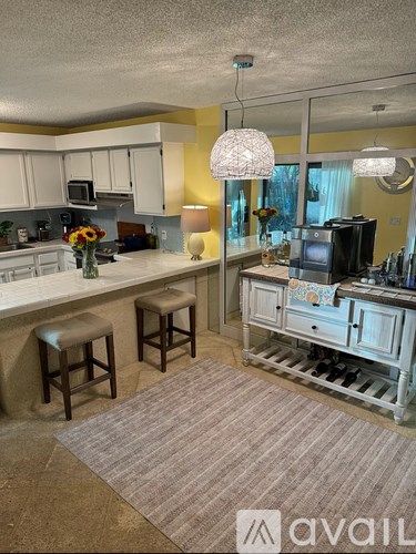 A kitchen with white cabinets and a countertop with a vase of flowers on it.