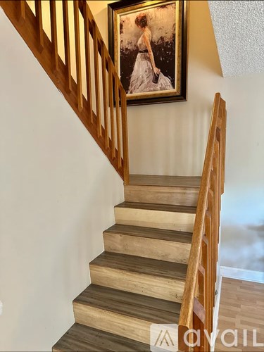 A staircase with wooden steps and a painting of a woman on the wall.