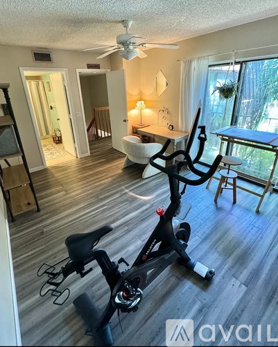 A room with a black exercise bike in the middle of it.