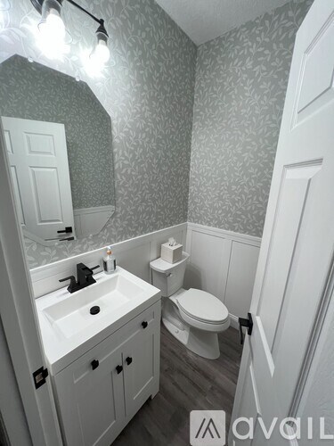 A bathroom with a toilet, sink, and mirror.