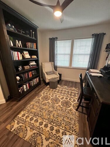 A room with a bookshelf, a chair, and a desk.
