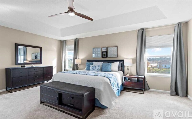 A bedroom with a large bed, a dresser, and a ceiling fan.