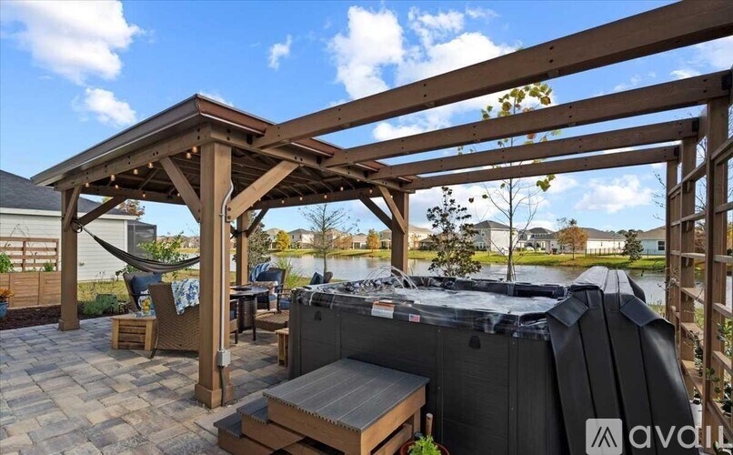 A hot tub is surrounded by a wooden pergola and a hammock.