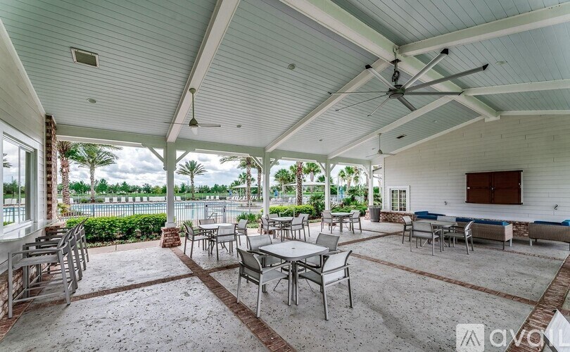 A covered patio with tables and chairs and a ceiling fan.