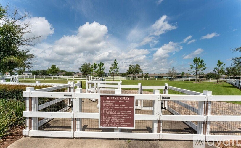 A sign in front of a fence that says Dog Park Rules.