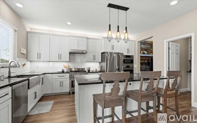 A kitchen with white cabinets and a black countertop.