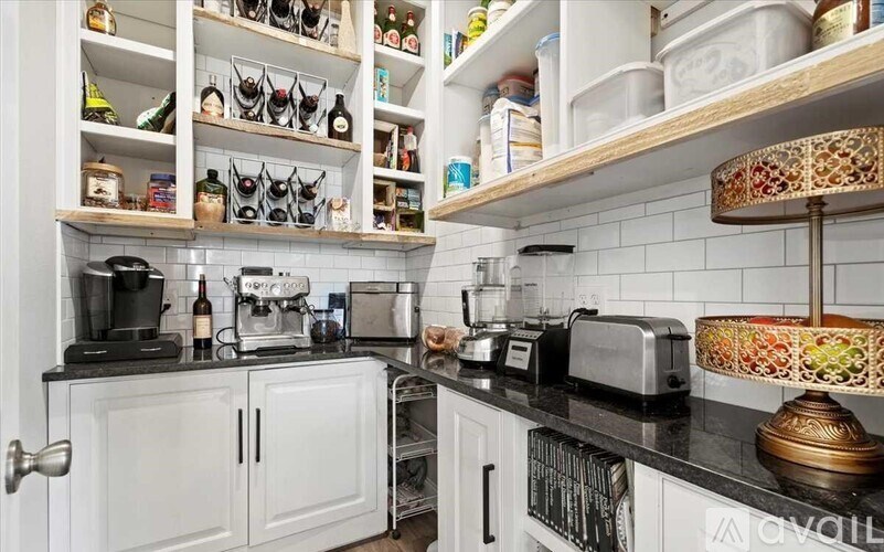 A kitchen with white cabinets and black countertops.