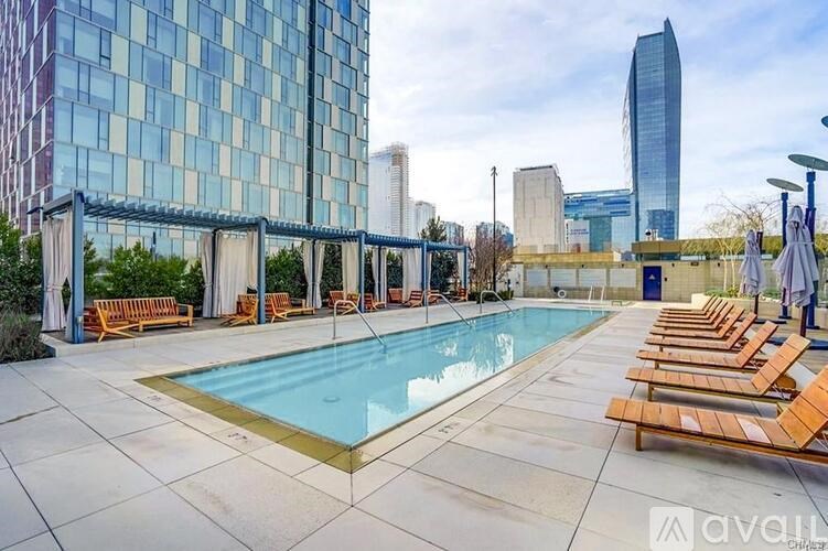 A large outdoor swimming pool with sun loungers and a glass building in the background.