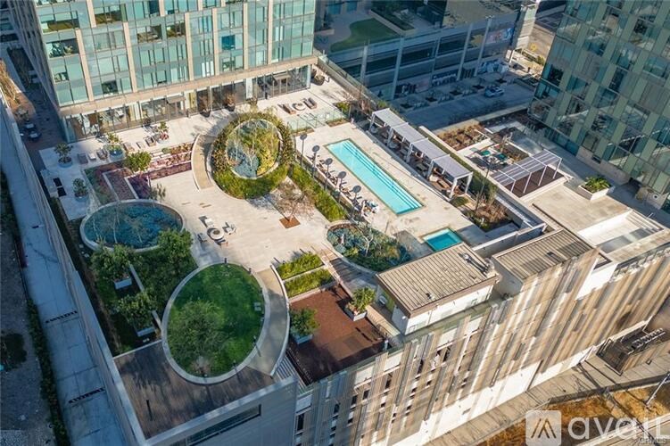 An aerial view of a courtyard with a pool and a green area surrounded by buildings.