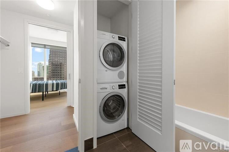 A washing machine is in a small room with a view of a cityscape through the window.