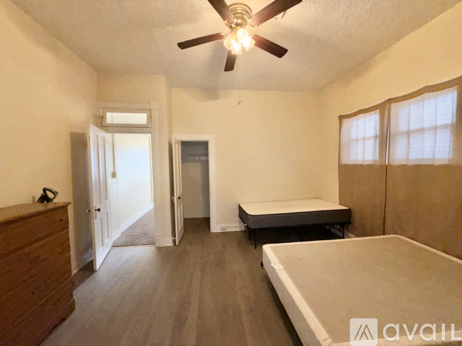 A room with a bed, a dresser, and a ceiling fan.