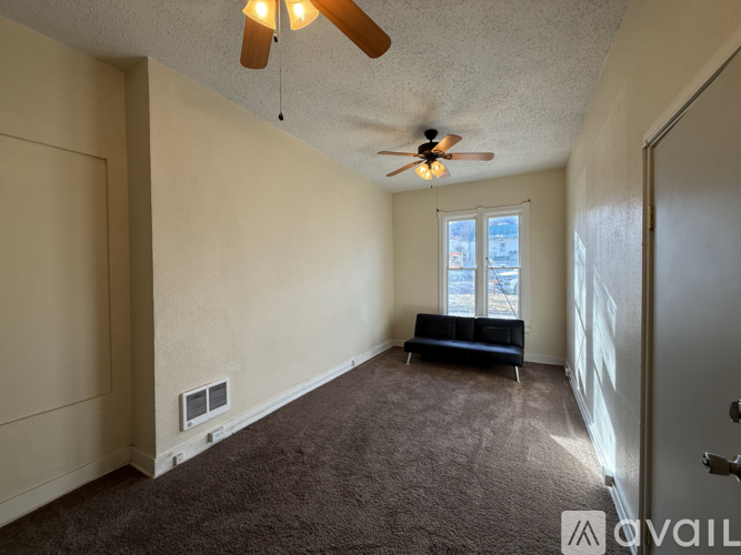 A room with a ceiling fan and a window with blinds.