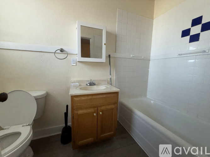 A bathroom with a toilet, sink, and a wooden cabinet.