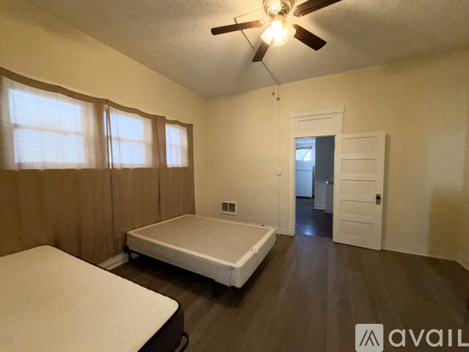 A bedroom with a bed, a ceiling fan, and a door leading to another room.