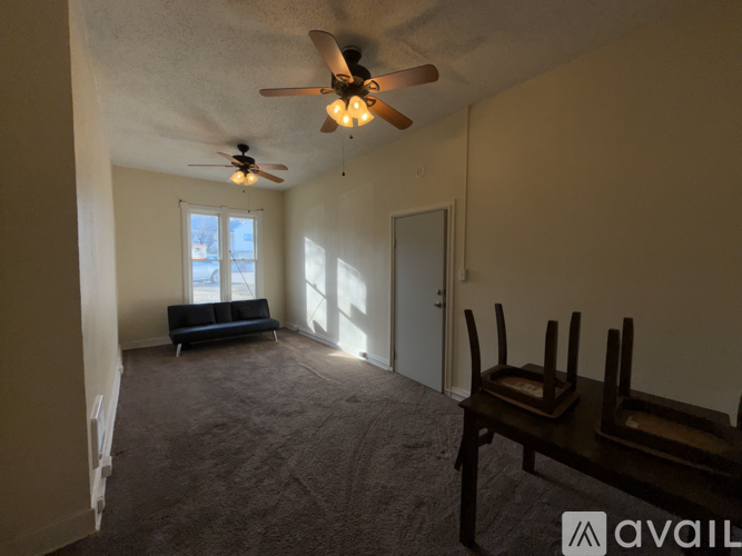 A living room with a couch, chairs, and a ceiling fan.