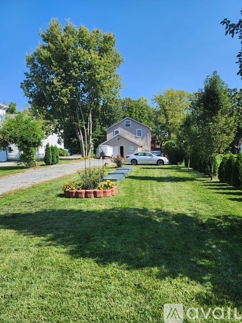 A well-kept lawn with a house and trees in the background.