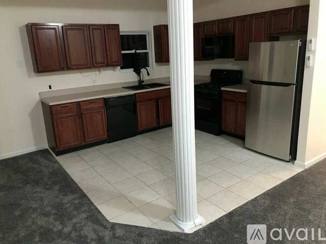 A kitchen with brown cabinets and a white column in the middle.